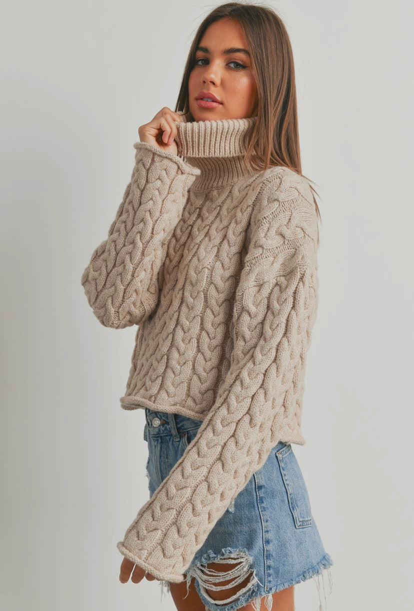 a woman wearing a turtle neck sweater and ripped denim shorts