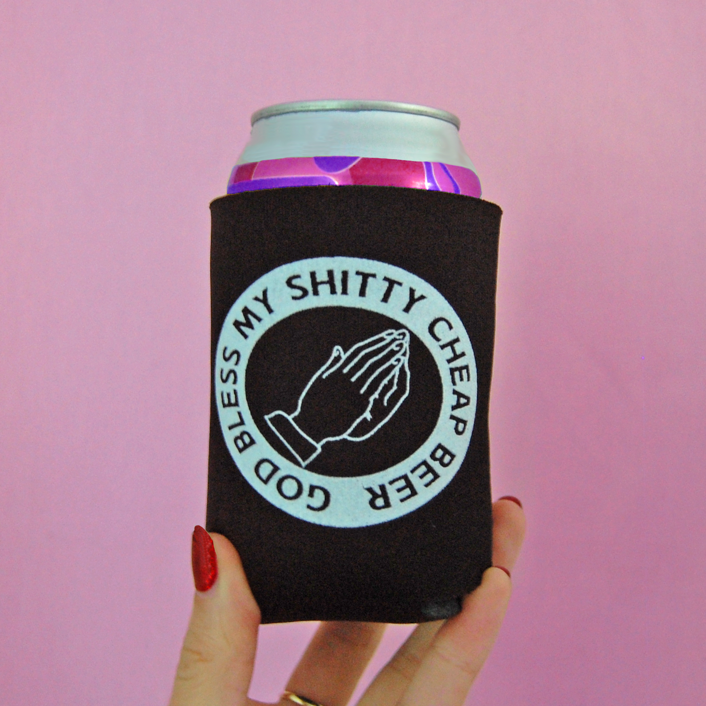 a hand holding a can cooler with a pink background
