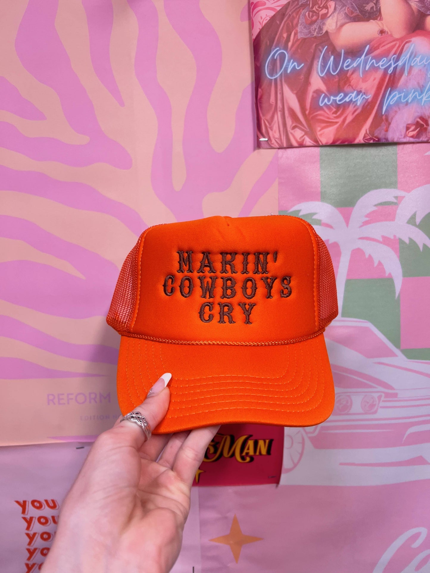 a hand holding an orange hat that says narn cowboys cry